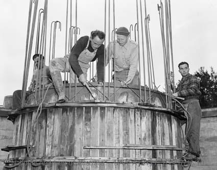 Black and white photograph of four migrant carpenters from Ukraine, Germany, Norway and Malta working on the new sewerage project at Western Creek, Canberra