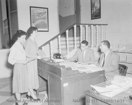 Black and white photograph of Department of Immigration officers at a desk in Malta, taking first enquiries about migration to Australia